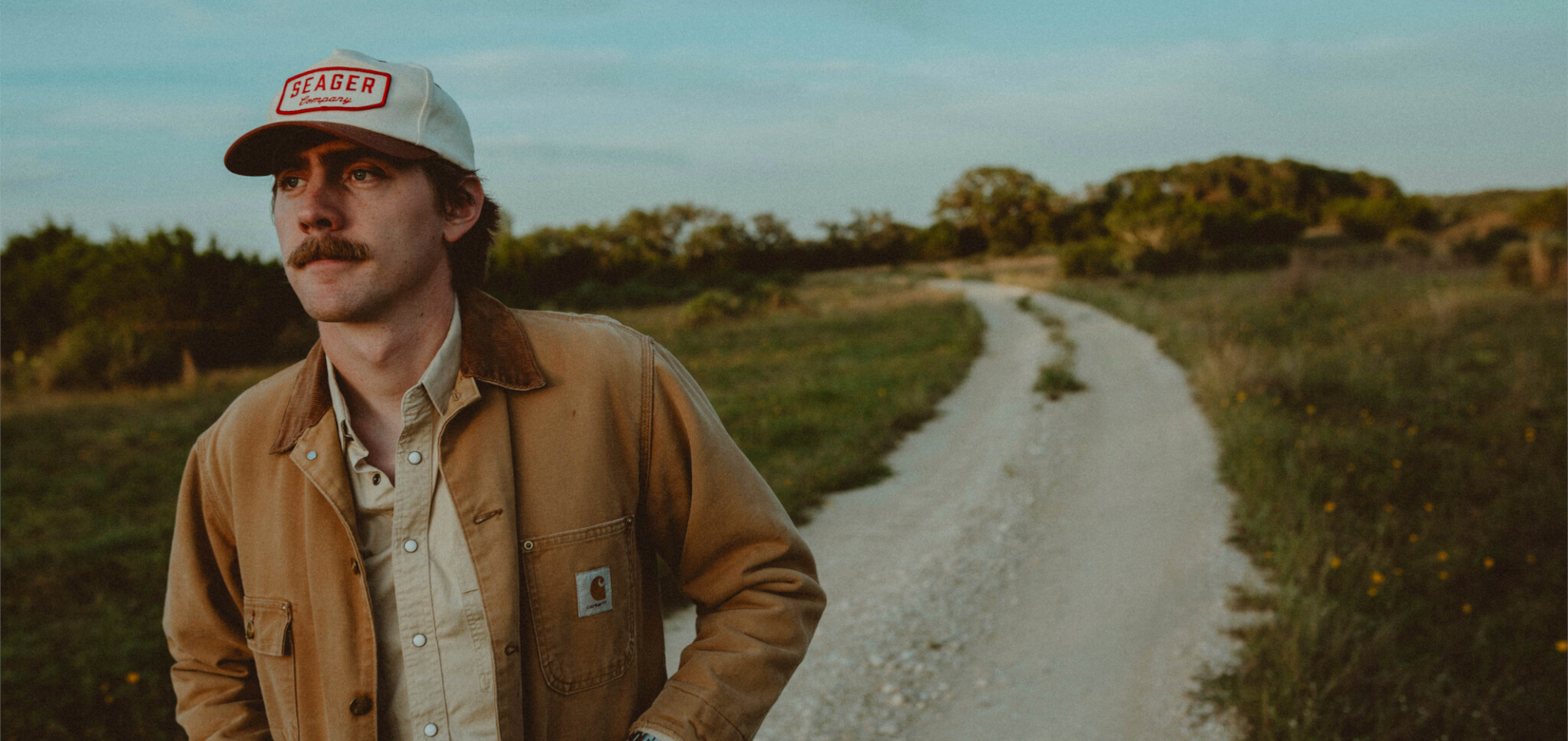 Homme avec une casquette et veste beige foncé dans la nature